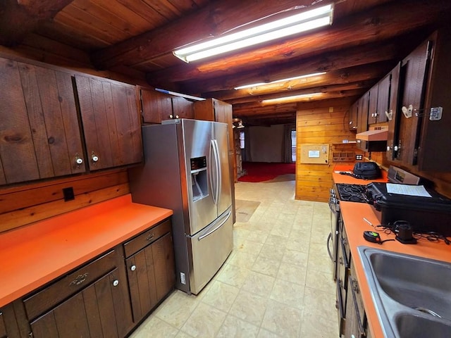 kitchen featuring stainless steel refrigerator with ice dispenser, wood ceiling, sink, beam ceiling, and wood walls