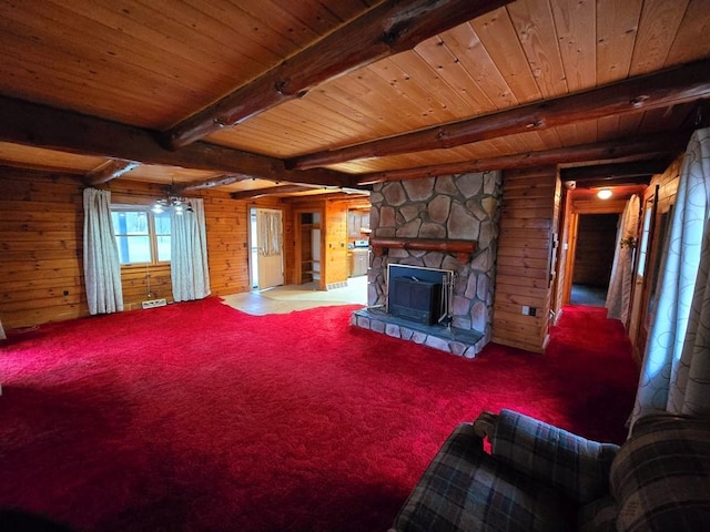 carpeted living room featuring beamed ceiling, wooden ceiling, a fireplace, and wooden walls