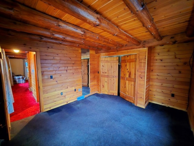 unfurnished bedroom featuring wood walls, beamed ceiling, wooden ceiling, and dark colored carpet