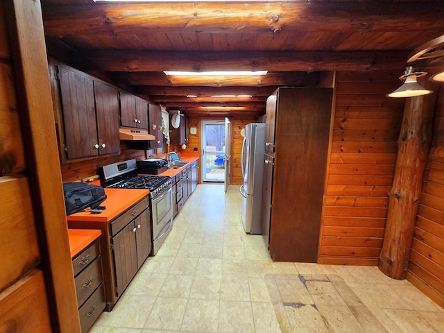 kitchen featuring sink, wooden walls, appliances with stainless steel finishes, beam ceiling, and wood ceiling