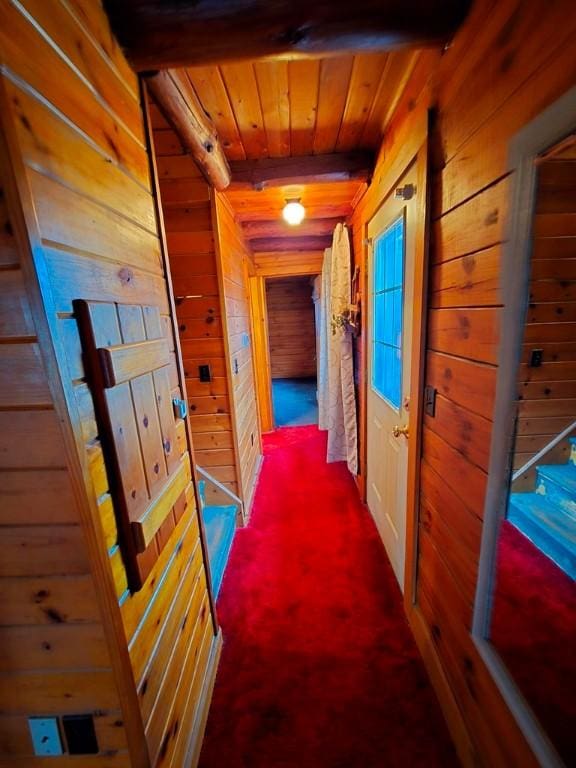 hall featuring wooden walls, carpet, and wooden ceiling