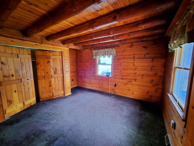 interior space featuring beamed ceiling, dark carpet, wooden ceiling, and wood walls