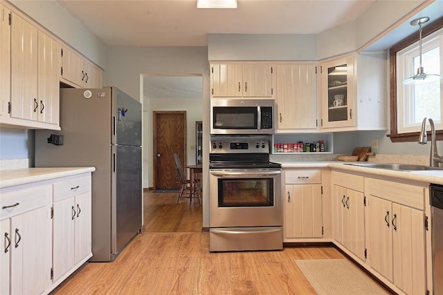 5219 W 52nd St, Fairview, PA 16415 - kitchen with appliances with stainless steel finishes, light countertops, light wood finished floors, glass insert cabinets, and pendant lighting