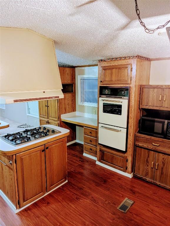 kitchen with dark hardwood / wood-style floors, a textured ceiling, and white appliances