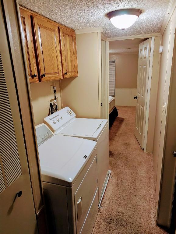 washroom with cabinets, separate washer and dryer, light carpet, and a textured ceiling