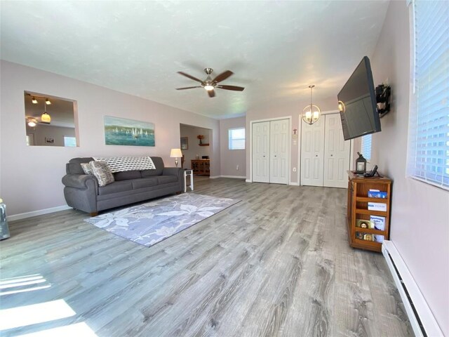 1986 Providence Dr, Jamestown, PA 16134 - living area featuring light wood-style floors, baseboards, baseboard heating, and ceiling fan with notable chandelier