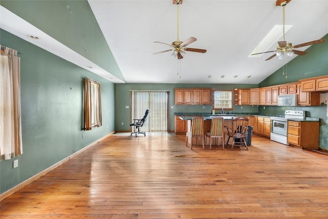 kitchen featuring a kitchen bar, white appliances, high vaulted ceiling, a center island, and light hardwood / wood-style floors