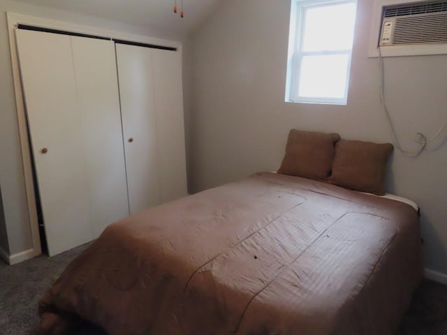 carpeted bedroom featuring a wall mounted air conditioner, vaulted ceiling, and a closet