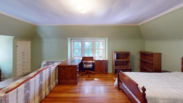 unfurnished bedroom featuring vaulted ceiling, crown molding, and light hardwood / wood-style flooring