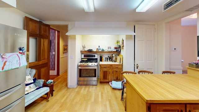 kitchen with premium range hood, decorative backsplash, stainless steel appliances, and light wood-type flooring