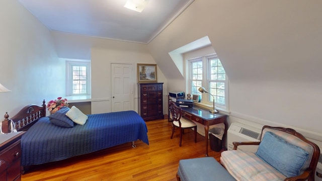 bedroom with a wall mounted air conditioner and light wood-type flooring