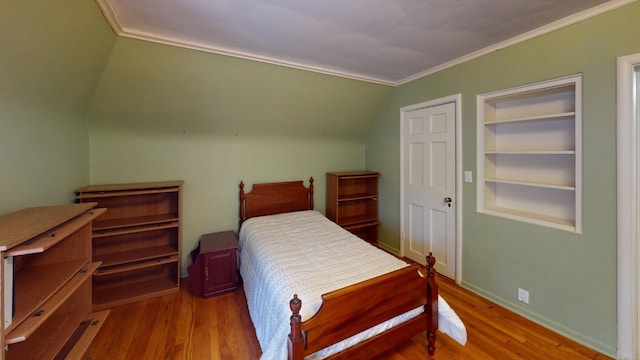 bedroom with wood-type flooring, vaulted ceiling, and crown molding