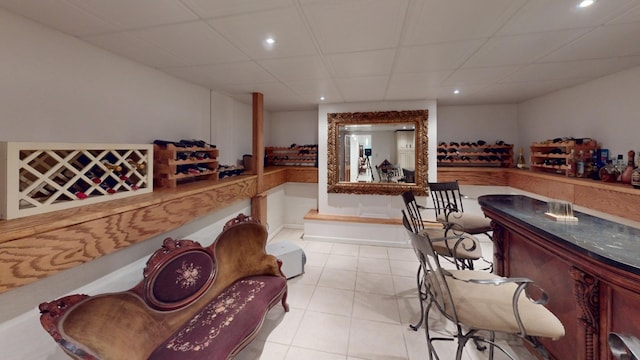 interior space with bar area, a drop ceiling, and light tile patterned floors