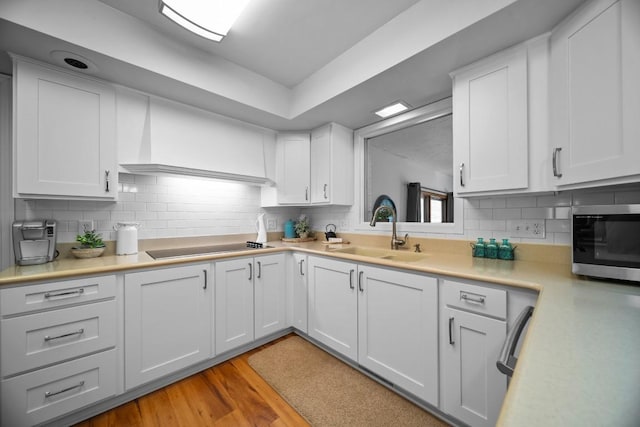 5124 W Ridge Rd, Erie, PA 16506 - kitchen featuring stainless steel microwave, light countertops, white cabinets, light wood-type flooring, and tasteful backsplash