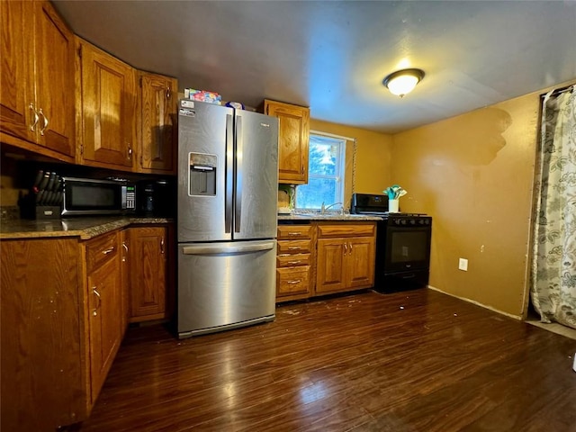 kitchen featuring black appliances, dark hardwood / wood-style flooring, sink, and light stone counters