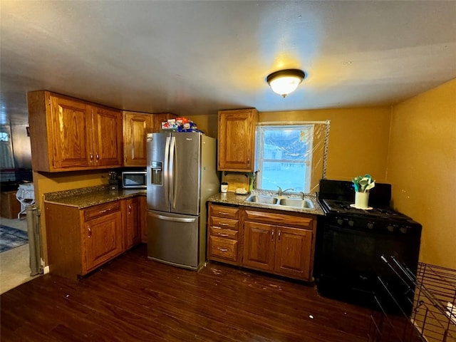 kitchen featuring dark hardwood / wood-style floors, stone counters, sink, stainless steel fridge with ice dispenser, and black gas range oven