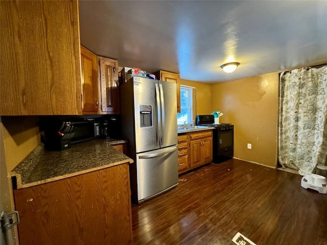 kitchen with stainless steel refrigerator with ice dispenser, dark hardwood / wood-style flooring, gas stove, and sink