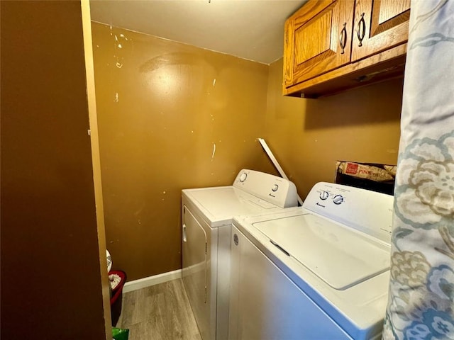 laundry room with hardwood / wood-style floors, independent washer and dryer, and cabinets