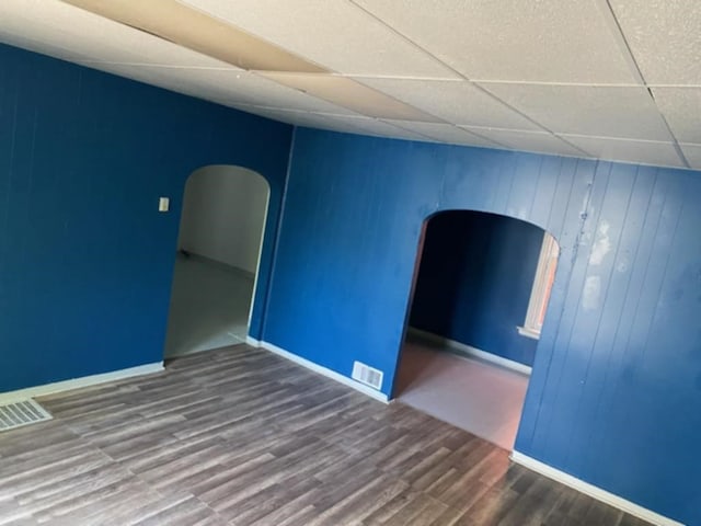 spare room with a paneled ceiling and dark hardwood / wood-style floors