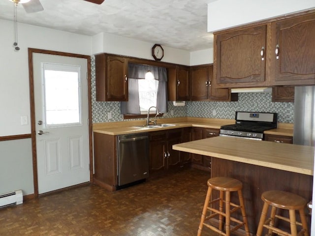 kitchen featuring a breakfast bar, sink, baseboard heating, tasteful backsplash, and stainless steel appliances