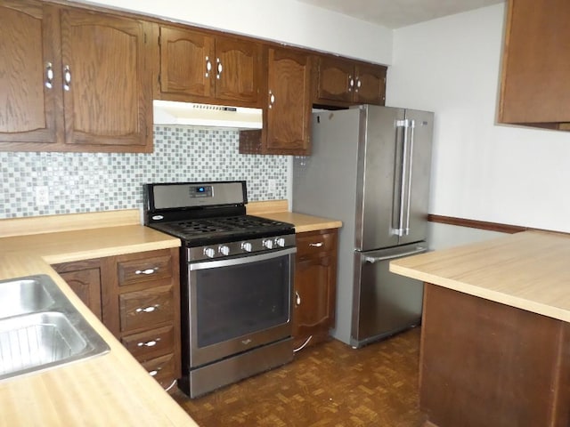 kitchen with sink, backsplash, appliances with stainless steel finishes, and dark parquet flooring