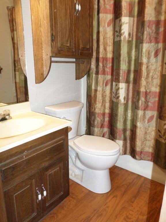 full bathroom with hardwood / wood-style floors, vanity, shower / bath combination with curtain, and toilet