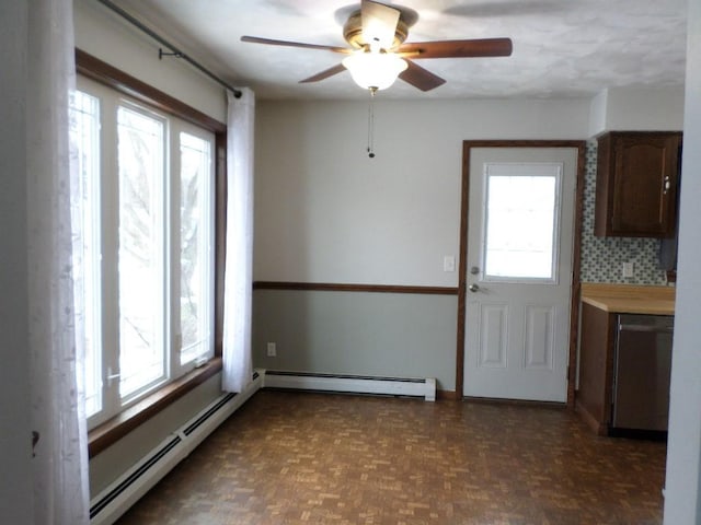 unfurnished dining area featuring baseboard heating, dark parquet flooring, and a healthy amount of sunlight