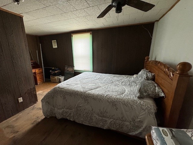 bedroom with light hardwood / wood-style flooring, ceiling fan, and wood walls