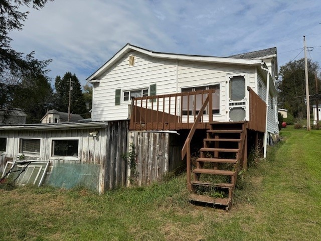 rear view of house featuring a lawn and a deck