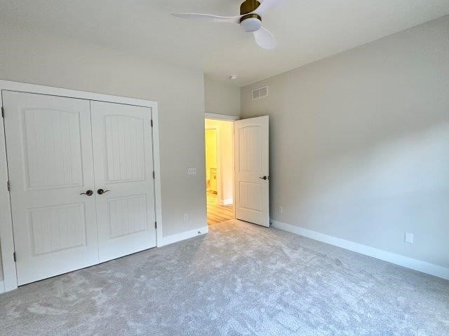 unfurnished bedroom featuring carpet flooring, ceiling fan, and a closet