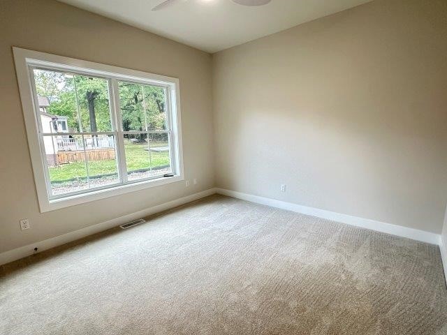 carpeted spare room featuring ceiling fan