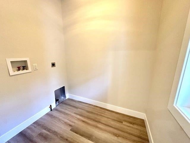 clothes washing area with electric dryer hookup, hookup for a washing machine, and hardwood / wood-style floors