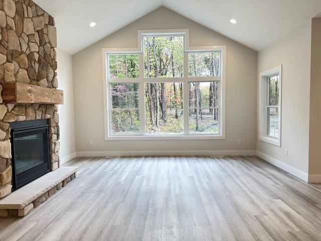 unfurnished living room featuring a fireplace and lofted ceiling