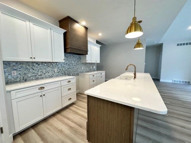 4655 Elsie Rd Unit 1, Erie, PA 16511 - kitchen featuring light wood-style floors, white cabinets, tasteful backsplash, decorative light fixtures, and light countertops
