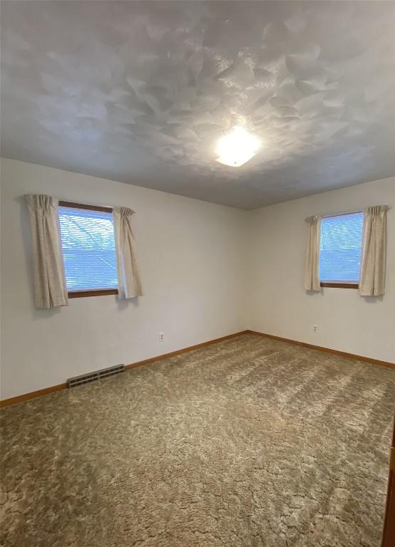 spare room featuring a textured ceiling and carpet floors