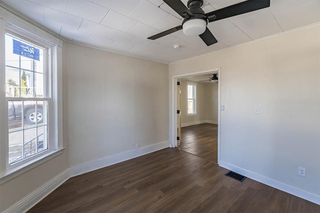 empty room with dark wood-style floors, plenty of natural light, and baseboards