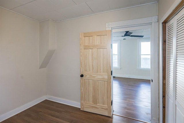 spare room with dark wood finished floors, a ceiling fan, and baseboards