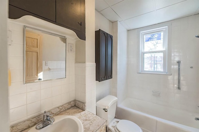 bathroom featuring toilet, washtub / shower combination, vanity, and tile walls