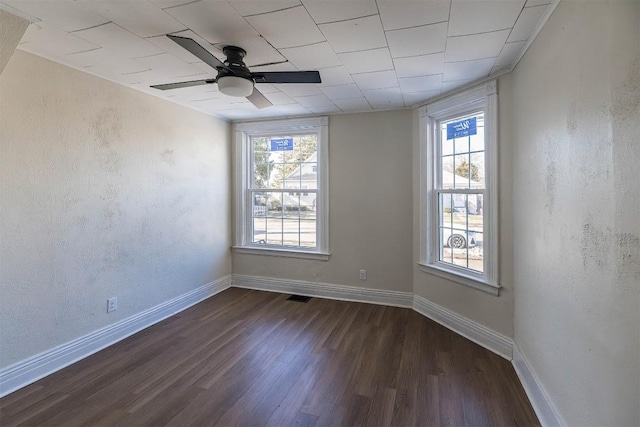 unfurnished room with dark wood-style flooring, visible vents, a textured wall, ceiling fan, and baseboards