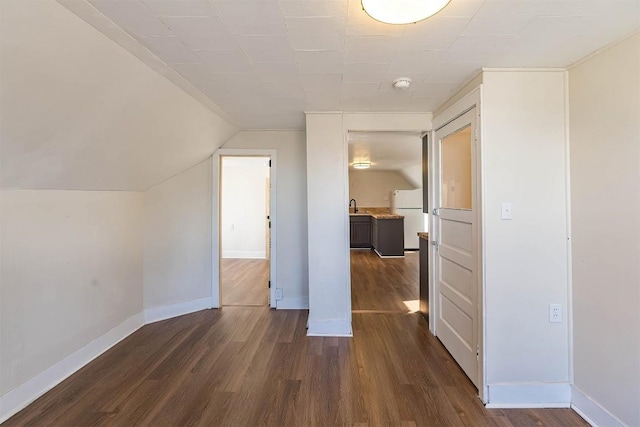 bonus room featuring dark wood-style floors, a sink, vaulted ceiling, and baseboards