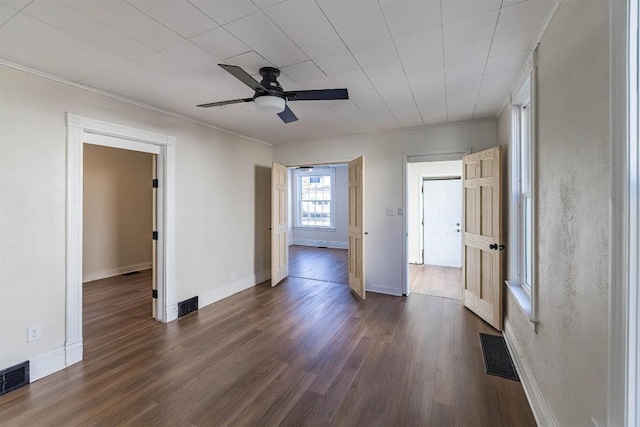 empty room featuring visible vents, dark wood finished floors, and baseboards