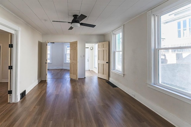 spare room with dark wood-type flooring, visible vents, and baseboards