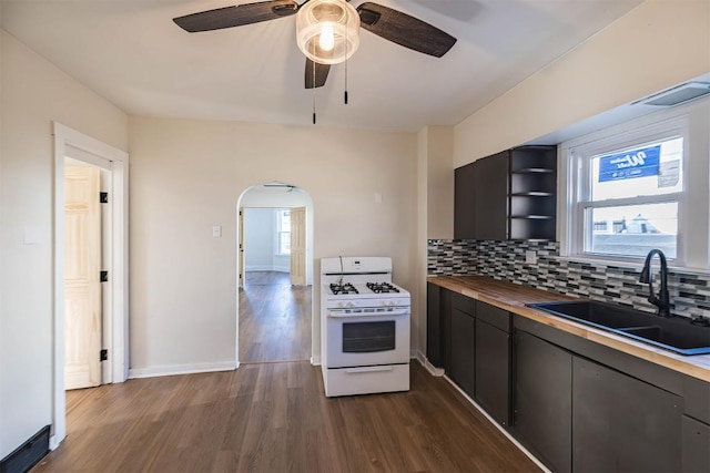 kitchen with butcher block counters, a sink, decorative backsplash, dark wood-style floors, and white gas range