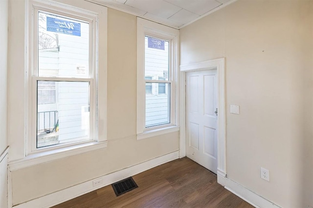 interior space with dark wood-type flooring, visible vents, and baseboards