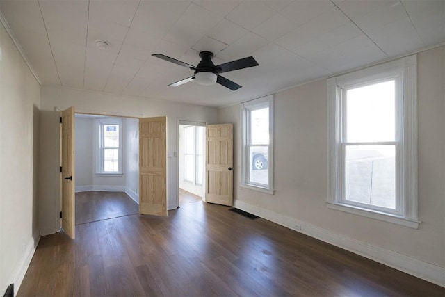 unfurnished room with baseboards, visible vents, dark wood-style floors, ceiling fan, and ornamental molding