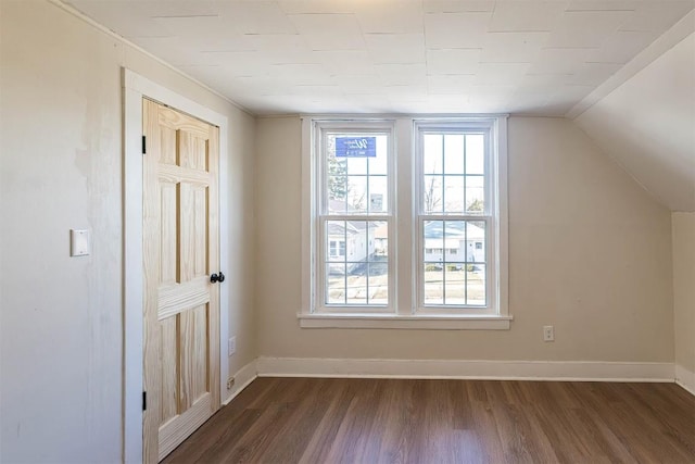 additional living space featuring vaulted ceiling, dark wood-type flooring, and baseboards