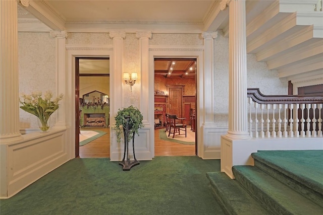 interior space featuring beam ceiling, ornate columns, crown molding, and carpet floors