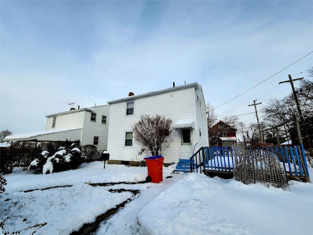 snow covered rear of property with a wooden deck