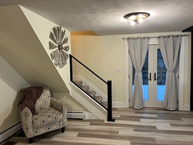 interior space featuring a baseboard heating unit, wood finished floors, and french doors