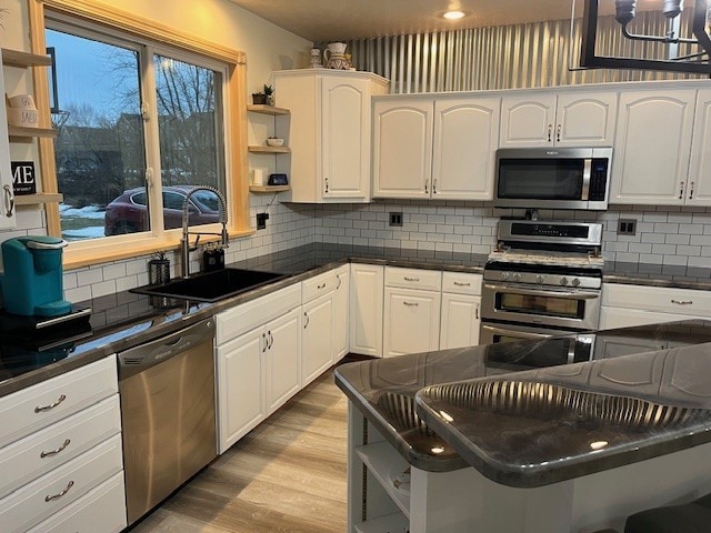 kitchen featuring dark countertops, a sink, stainless steel appliances, and open shelves